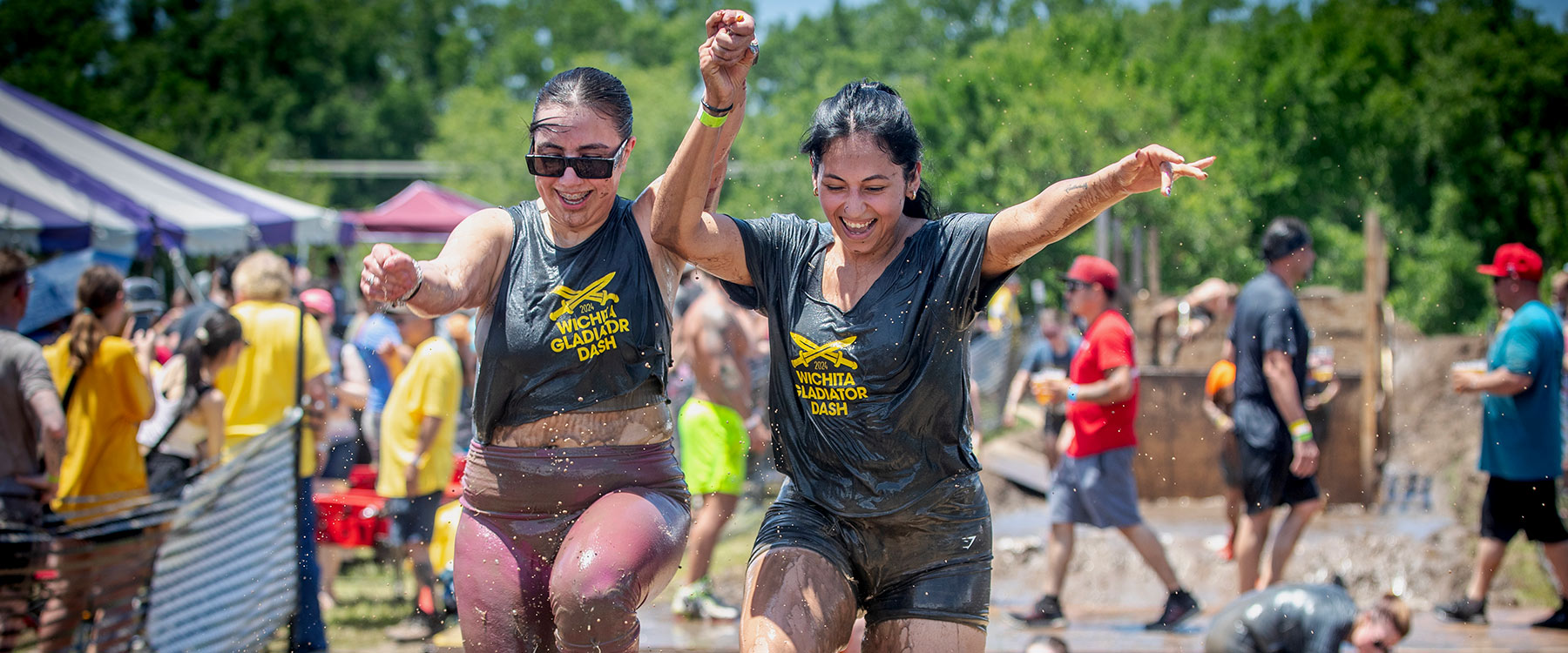 Two Muddy Women Running While Holding Hands