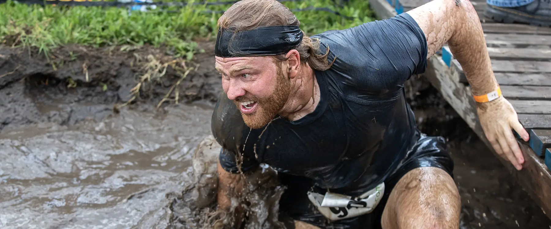 Athletic Man Running Through a Muddy Obstacle