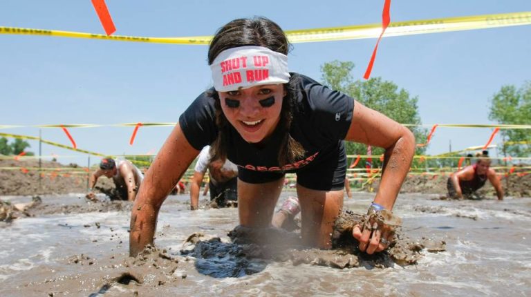 Woman Crawling Through Mud While Smiling